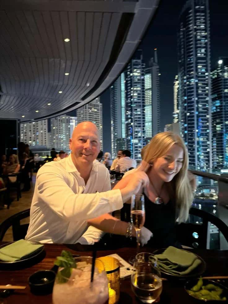Couple dining on a rooftop terrace with a city skyline at night