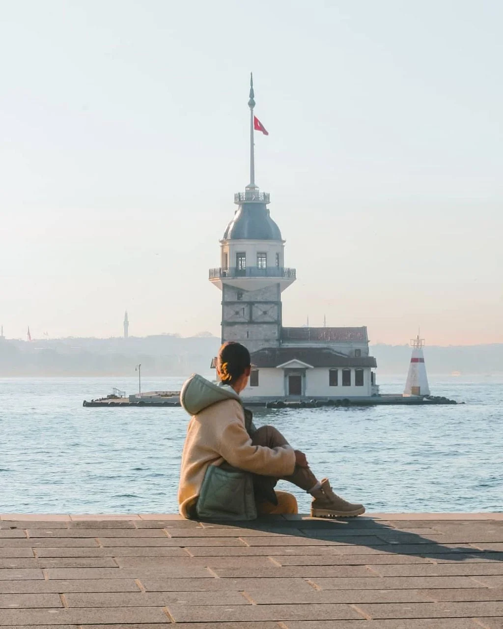 Woman sitting by the Bosphorus facing Maiden's Tower in Istanbul